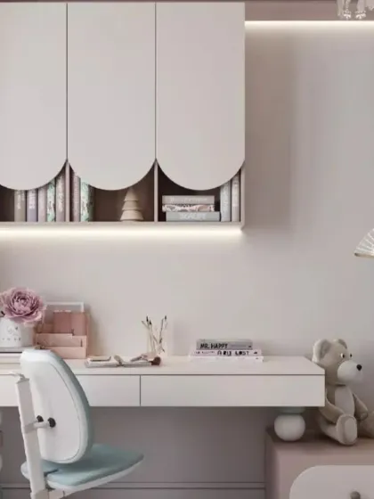 A clean and contemporary study area with a white desk, overhead cabinets with scalloped edges, and soft, integrated lighting. This design is perfect for a calm and focused workspace.