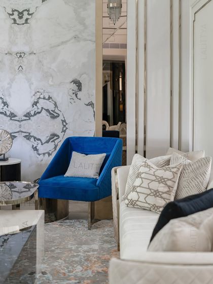 A close-up of the accent seating, where a cobalt blue velvet chair adds a strong pop of color against the neutral sofa and marble wall. It’s these intentional details that bring a space to life.