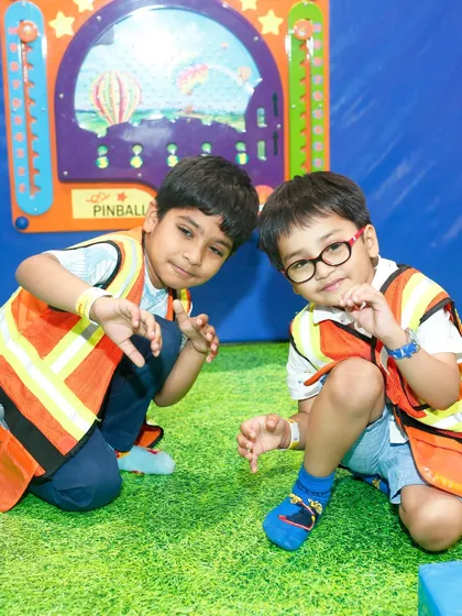 Two boys dressed as construction workers pose for the camera in our pretend play zone.
