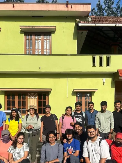 A large group of trekkers ready to start their journey, standing in front of their transport van and a local homestay. This is where the adventure begins.