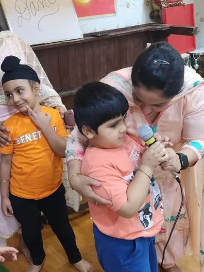Even our youngest campers get a chance to shine. Here, a teacher helps a little boy hold the microphone as he sings for his friends.