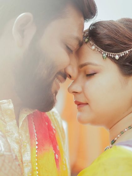 A tender, close-up moment with the couple's foreheads touching, their eyes closed, during a quiet moment in their haldi ceremony.