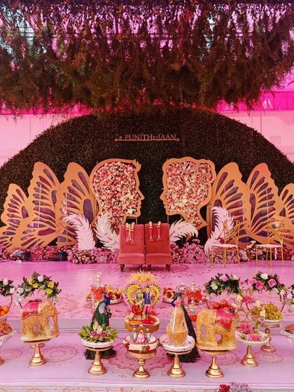 A grand butterfly-themed stage with a green hedge backdrop, perfect for a whimsical and romantic event.