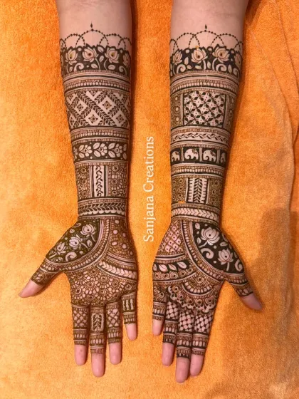 Full coverage bridal mehndi that goes all the way up the arms. This design is packed with details, including geometric checks, floral bands, and tiny elephants.