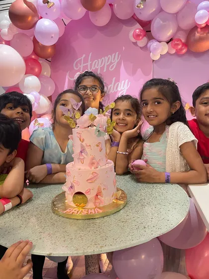 A beautiful butterfly-themed cake cutting moment. The pink balloon arch with delicate butterfly accents created a perfect photo opportunity for the birthday girl and her friends.