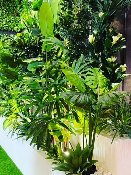 A close-up of a planter box filled with a dense mix of artificial tropical plants. These can be used as dividers or to line a wall or walkway.