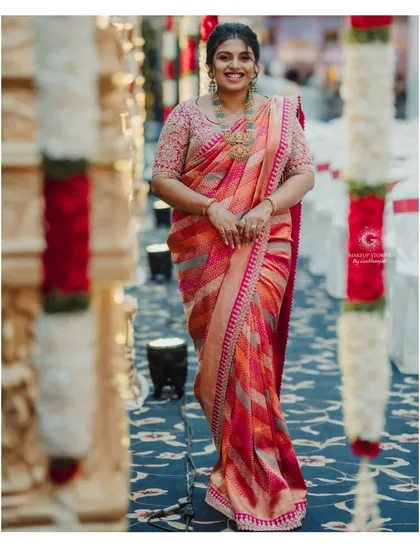 A full-length shot of Varsha. The elegant, messy bun is a great choice for balancing a heavily embroidered saree, keeping the overall look from feeling too heavy.