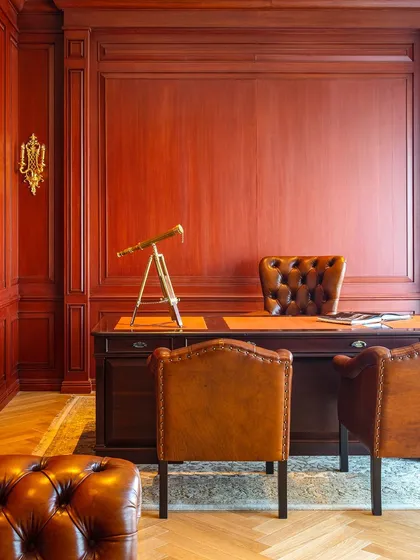 The director's desk at Paras Buildtech is set against a backdrop of rich, red-toned wood paneling. The space is designed to feel classic and powerful, reflecting the client's dedication to quality and excellence.