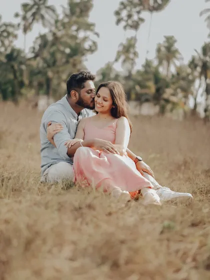 A romantic portrait of the couple sitting in a field of tall grass, adding a different texture and feel to their coastal pre-wedding shoot.