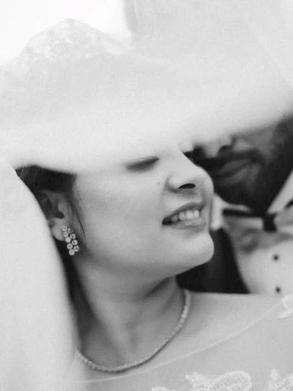 A soft and dreamy black and white portrait of the couple under the veil. The focus is on the bride's happy, relaxed expression.