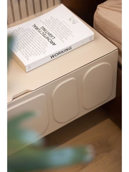 The custom bedside table features clean lines and subtle, carved details, blending seamlessly with the overall design.