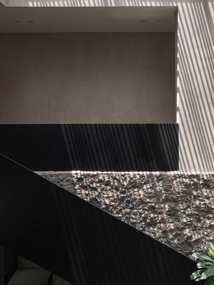 A detail of the architectural play of light and shadow against a textured stone wall. This is a core concept of the GAIA house, where natural elements create ever-changing art.