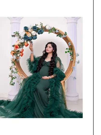 A beautiful solo portrait featuring one of our green tulle gowns. The mom-to-be is seated on a floral-adorned circular prop, creating a look that is both elegant and whimsical.