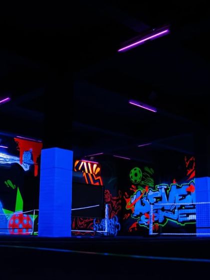 Another perspective of the Level One Arena under UV light. The artwork covers multiple walls, ensuring that the entire space is filled with glowing, dynamic art that enhances the gaming and sporting experience.
