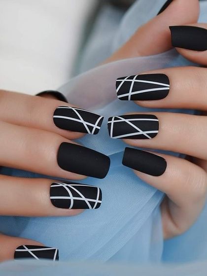 A modern and graphic design featuring a matte black base with crisp white abstract lines on square-shaped nails.