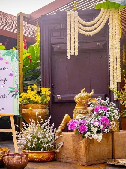 The welcome area for a South Indian wedding, featuring a traditional Chettinad door, a brass Nandi, and vibrant floral arrangements.