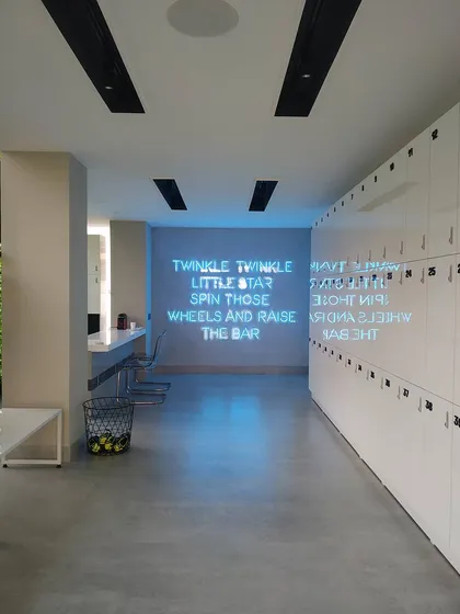 The locker and hallway area of the studio, featuring a custom neon sign with a motivational quote. This element adds a playful and branded touch to a functional space, enhancing the overall member experience.