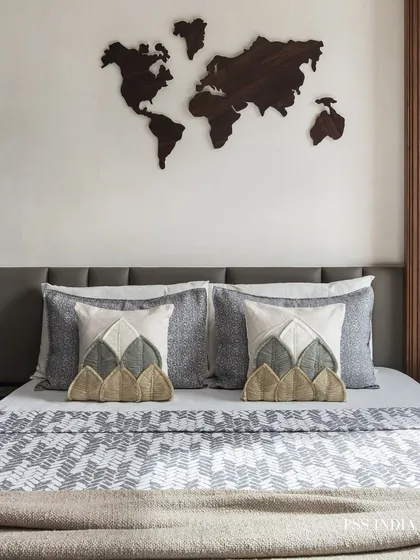 For the travel lover, this bedroom features a wooden world map as wall art. The look is grounded with earthy, textured pillows and a patterned bedspread, creating a space that inspires adventure.