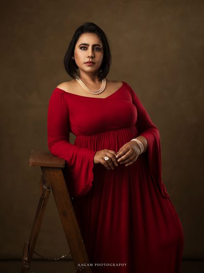 This portrait in a bell-sleeved red gown has a regal, classic feel. The pose is confident and the lighting is soft, creating a truly artistic maternity photograph.