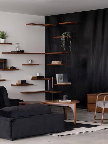 In our Ebony & Ivory project, we created a monochromatic living space with a plush black sofa and a dramatic black fluted wall. The floating wooden shelves add warmth and provide a canvas for curated decor.