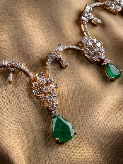 A detailed view of the Aurora Verde necklace, showcasing the sharp lines and vivid pear-shaped emerald drops.