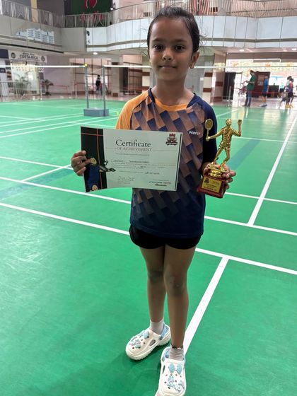 Kashvi, our U-11 winner at the Racket Rider Tournament, proudly holding her certificate and trophy on the court where she trains every day.