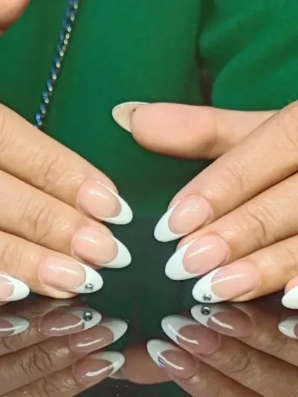 A classic French manicure on almond nails, made special with a single tiny rhinestone placed at the base of each tip.