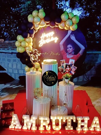 A closer view of the personalized birthday decor, highlighting the custom backdrop with a photo and the arrangement of pictures on the plinths.