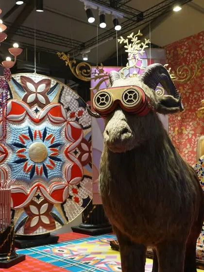 A taxidermy sheep wearing futuristic goggles stands in the 'Bad Taste?' installation. This surreal and humorous juxtaposition is central to the theme's critique of conventional taste.