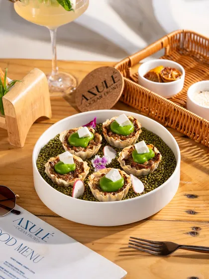 Creative canapés served on a bed of green lentils. The unique presentation makes this dish stand out.