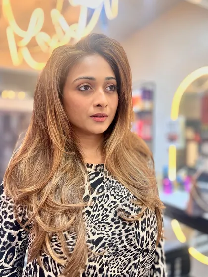 Another shot of the honey-blonde balayage, with the salon's neon sign in the background. The color looks rich and vibrant, perfect for someone in the fashion industry.