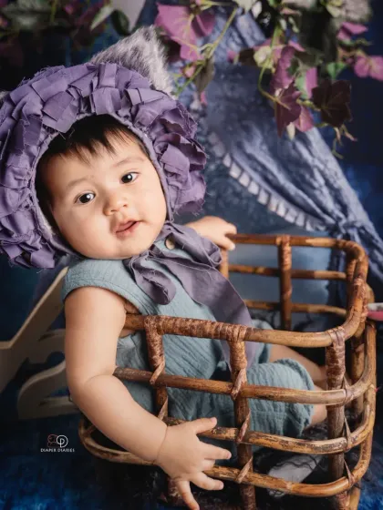 Celebrating the half-birthday milestone at six months old. This happy baby sits in a wicker basket with a '1/2' sign, showing off a huge, infectious giggle.