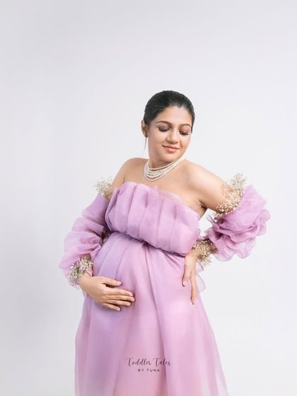 A moment of quiet contemplation. This pose, with the mother looking down at her bump, is filled with love and serene anticipation. The delicate details of the gown shine in this shot.