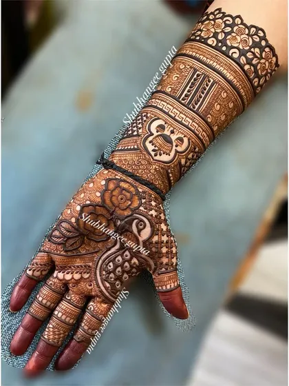 A traditional design for the back of the hand, featuring a peacock, a rose, and a small Ganesh motif. It's a beautiful blend of different classic elements.