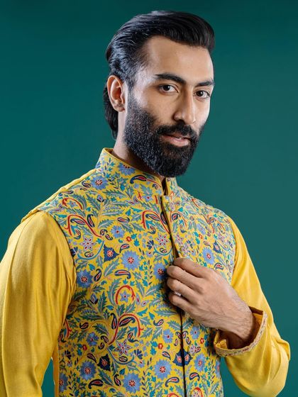 A close-up of a yellow Jawahar jacket with a blue and green paisley print. This premium piece is a quintessential fit for the winter wedding season, bringing sunshine to any soirée.
