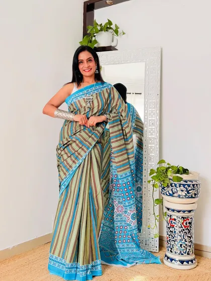 A striped cotton Mulmul saree in earthy tones of green, brown, and blue. This is a unique and stylish option for work or casual outings.