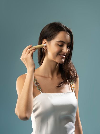 A lifestyle shot of a model using a personal grooming product. Her happy expression and the clean background make the product feel approachable and effective.