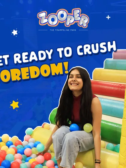Get ready to crush boredom. A guest smiles while sitting at the edge of our huge, colorful ball pit.