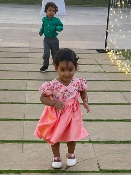 A candid shot of a toddler taking her first stylish steps in a pink floral dress. My designs are made to be comfortable for even the littlest fashionistas.