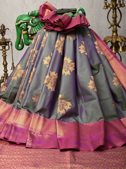 This grey and magenta silk saree offers a contemporary take on traditional weaves. The body features large floral butas, and the vibrant pink border provides a beautiful contrast.