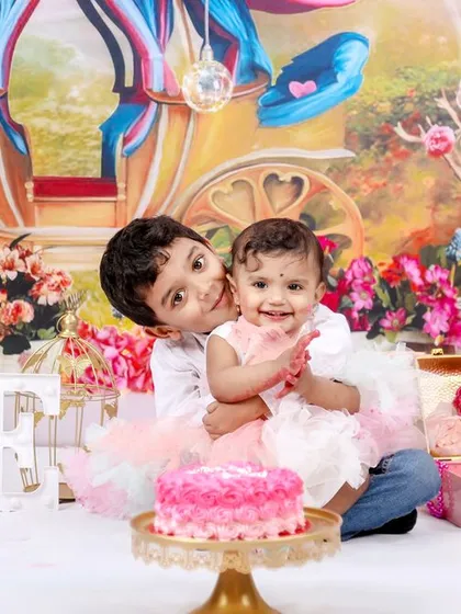 A fun and messy cake smash session to celebrate a first birthday. This little girl and her older brother are enjoying the celebration in a colorful, princess-themed studio setup.