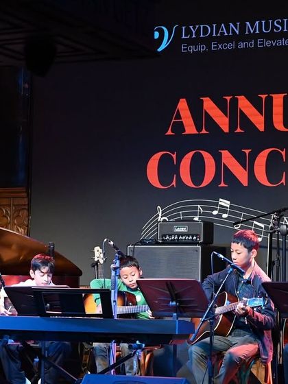 The Guitar Ensemble on stage, featuring a mix of acoustic guitars and ukuleles. This highlights the variety of string instruments our students can learn and master at the academy.