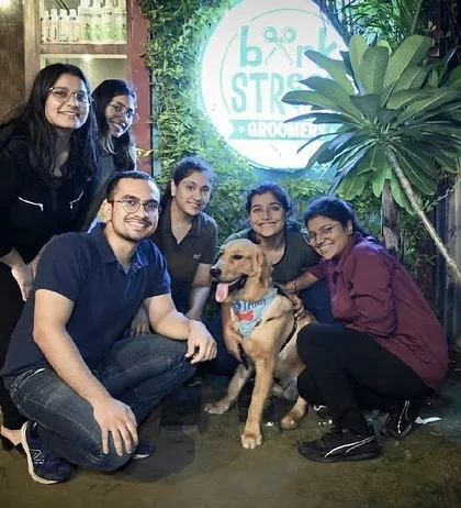 A group of friends posing with a happy doggo right by our outdoor sign. It's the perfect spot for a group photo.
