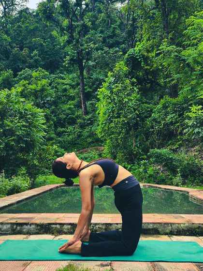 Practicing Ustrasana (Camel Pose) by the water in Rishikesh. The natural surroundings amplify the heart-opening benefits of this asana.