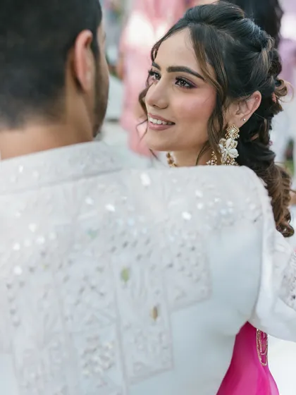 A candid moment showing the bride's romantic hairstyle from the side, highlighting the soft curls and intricate braids.
