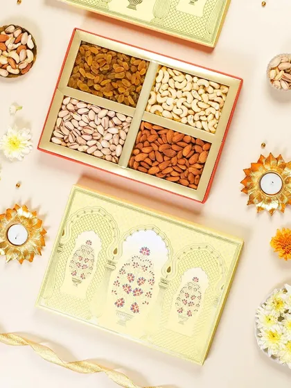 A festive flatlay of a yellow dry fruit gift box with traditional Indian arch designs. The arrangement with flowers and diyas creates a warm and inviting look for a Diwali catalog.