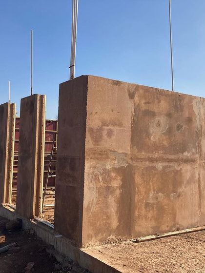 The finished rammed earth walls stand ready for the roof structure at the Unnathi Farm site.