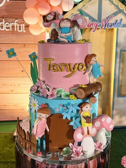 The beautifully detailed birthday cake for the fairy-themed party, adorned with little fairy figurines, flowers, and mushrooms.