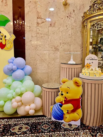 A dessert corner from the Winnie the Pooh party, featuring a character cutout and themed cake stands.