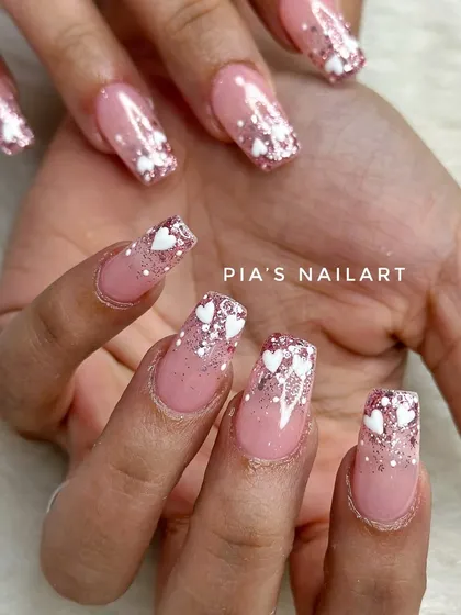 Glitter ombre nails with cute little white hearts. A sweet and sparkly design.